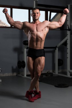 İyi eğitilmiş vücudunu gösteren genç bir adamın portresi - kaslı atletik vücut geliştirici spor sonrası vücut geliştirme modelliği pozu