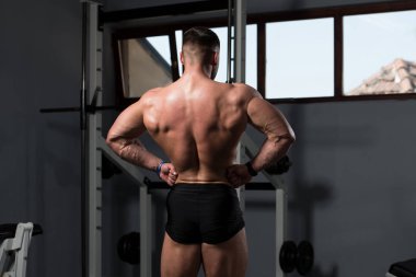Yakışıklı Genç Adam Spor Salonunda Güçlü Duruyor ve Kaslarını Geriyor - Kas Atletik Vücut Geliştirici Spor Sonrası Spor Pozisyonu