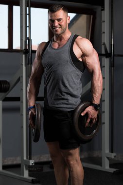 Elinde ağırlıkları olan genç bir adamın portresi.