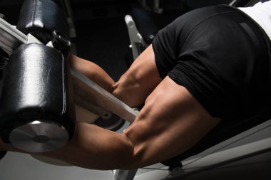 Spor salonundaki güçlü adam, kasları çalıştıran ve kalça kaslarını çalıştıran makine, kas geliştiren sporcu spor mankeni egzersizi.