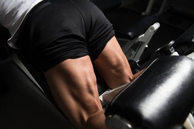 Spor salonundaki güçlü adam, kasları çalıştıran ve kalça kaslarını çalıştıran makine, kas geliştiren sporcu spor mankeni egzersizi.