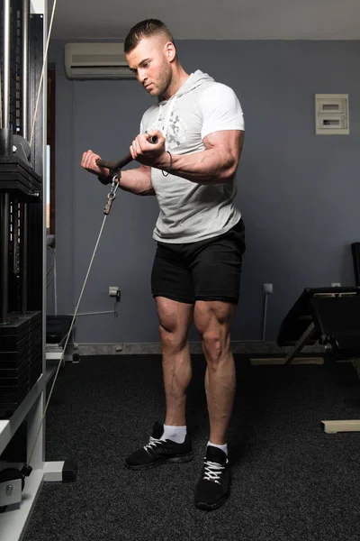 男子在健身房里用缆绳在机器上练习二头肌 — 图库照片