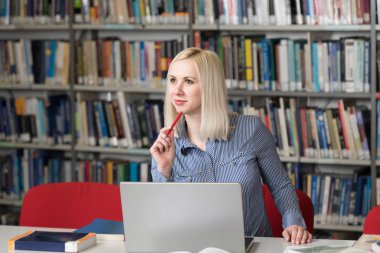 Bir yüksek okul kütüphanesinde çalışma kitapları ile güzel kız öğrenci