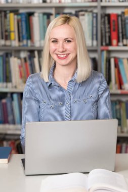 Bazı okul işi kütüphanede bir dizüstü bilgisayar ile bir çekici öğrenci portresi
