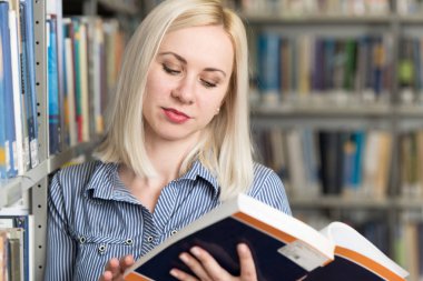 Bir yüksek okul kütüphanesinde çalışma kitapları ile güzel kız öğrenci