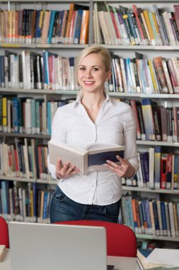 Bir yüksek okul kütüphanesinde çalışma kitapları ile güzel kız öğrenci