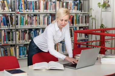 Bir yüksek okul kütüphanesinde çalışma kitapları ile güzel kız öğrenci