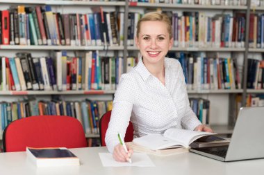 Bir yüksek okul kütüphanesinde çalışma kitapları ile güzel kız öğrenci