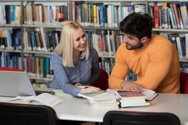 Kütüphanede dizüstü bilgisayar ve A yüksek çalışma kitapları yakışıklı iki üniversite öğrencileri üniversite kütüphanesi okul.