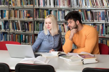 Kütüphanede dizüstü bilgisayar ve A yüksek çalışma kitapları yakışıklı iki üniversite öğrencileri üniversite kütüphanesi okul.