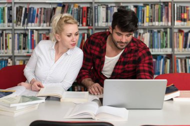 Kütüphanede dizüstü bilgisayar ve A yüksek çalışma kitapları yakışıklı iki üniversite öğrencileri üniversite kütüphanesi okul.