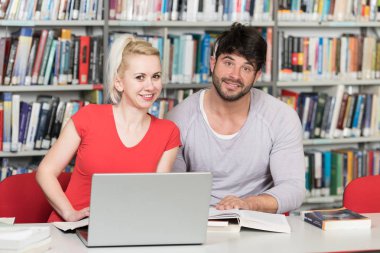 Kütüphanede dizüstü bilgisayar ve A yüksek çalışma kitapları yakışıklı iki üniversite öğrencileri üniversite kütüphanesi okul.