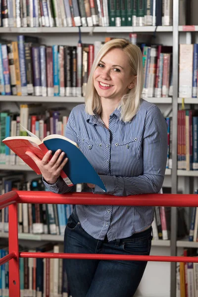 Bir yüksek okul kütüphanesinde çalışma kitapları ile güzel kız öğrenci