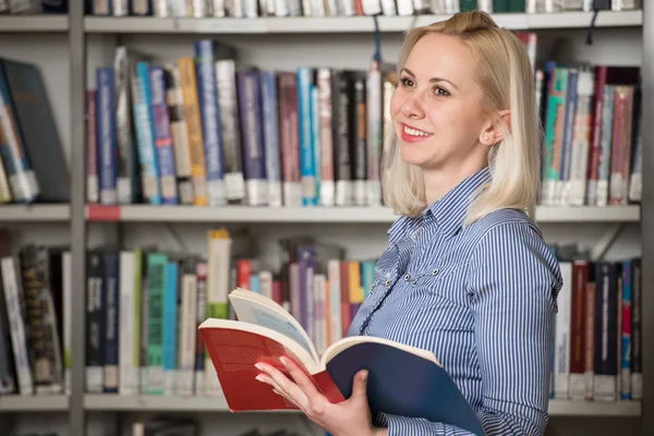 Kütüphanede - bulanık kitaplar arkada duran sarı saçlı güzel kadın