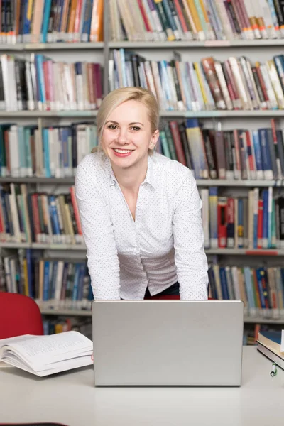 Kütüphanede - Laptop ve okuyan bir kavram ekrana bakarak tablo - Ajanda - sarı saçlı güzel kadın bulanık arka kitaplar