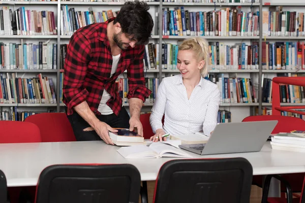 Dizüstü bilgisayar ve kitap ile birlikte çalışmak için soran Kütüphane yakışıklı adam için bir yüksek okul üniversite kütüphanesi, eser