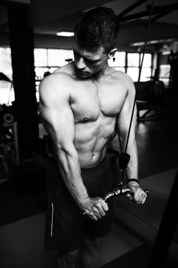 Spor salonundaki adam spor salonunda kablolu TV ile trisepslerini çalıştırıyor.