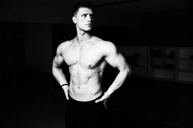 Yakışıklı Genç Adam Spor Salonunda Güçlü Duruyor ve Kaslarını Geriyor - Kas Atletik Vücut Geliştirici Spor Sonrası Spor Pozisyonu