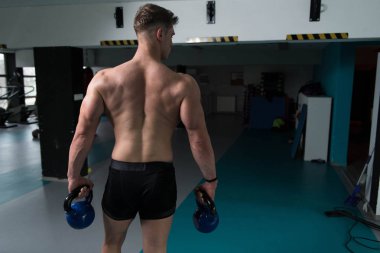 Genç adam su ısıtıcısı çan karanlık bir spor salonu - su ısıtıcısı-bell ile ağır egzersiz yapmak Bodybuilder olan çalışma dışarı