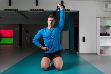 Genç adam su ısıtıcısı çan karanlık bir spor salonu - su ısıtıcısı-bell ile ağır egzersiz yapmak Bodybuilder olan çalışma dışarı