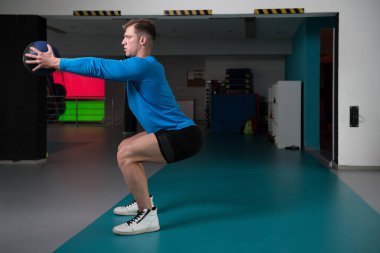 Yakışıklı genç adam kadrosu sağlık topu ile vücut geliştirme eğitim bir parçası olarak yapıyor