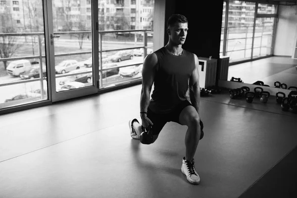 用水壶钟在一个黑暗的健身房 健美锻炼重配壶铃工作的年轻人 — 图库照片