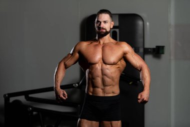 İyi eğitilmiş vücudunu gösteren genç bir adamın portresi - kaslı atletik vücut geliştirici spor sonrası vücut geliştirme modelliği pozu