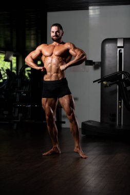 İyi eğitilmiş vücudunu gösteren genç bir adamın portresi - kaslı atletik vücut geliştirici spor sonrası vücut geliştirme modelliği pozu