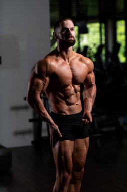 İyi eğitilmiş vücudunu gösteren genç bir adamın portresi - kaslı atletik vücut geliştirici spor sonrası vücut geliştirme modelliği pozu