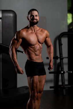 Yakışıklı Genç Adam Spor Salonunda Güçlü Duruyor ve Kaslarını Geriyor - Kas Atletik Vücut Geliştirici Spor Sonrası Spor Pozisyonu