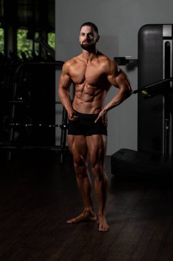 İyi eğitilmiş vücudunu gösteren genç bir adamın portresi - kaslı atletik vücut geliştirici spor sonrası vücut geliştirme modelliği pozu