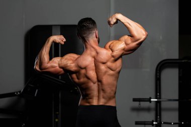 İyi eğitilmiş vücudunu gösteren genç bir adamın portresi - kaslı atletik vücut geliştirici spor sonrası vücut geliştirme modelliği pozu