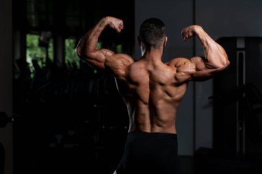 İyi eğitilmiş vücudunu gösteren genç bir adamın portresi - kaslı atletik vücut geliştirici spor sonrası vücut geliştirme modelliği pozu