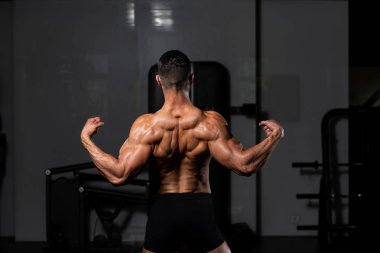 İyi eğitilmiş vücudunu gösteren genç bir adamın portresi - kaslı atletik vücut geliştirici spor sonrası vücut geliştirme modelliği pozu