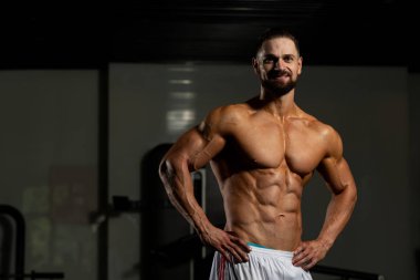 İyi eğitilmiş vücudunu gösteren genç bir adamın portresi - kaslı atletik vücut geliştirici spor sonrası vücut geliştirme modelliği pozu