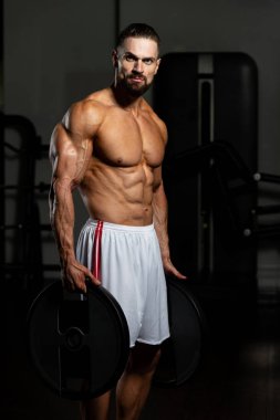 Elinde ağırlıkları olan genç bir adamın portresi.