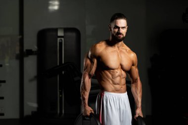 Elinde ağırlıkları olan genç bir adamın portresi.