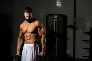 Elinde ağırlıkları olan genç bir adamın portresi.