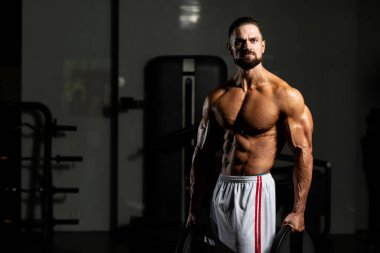 Elinde ağırlıkları olan genç bir adamın portresi.