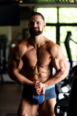 Yakışıklı Genç Adam Spor Salonunda Güçlü Duruyor ve Kaslarını Geriyor - Kas Atletik Vücut Geliştirici Spor Sonrası Spor Pozisyonu