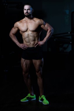 Yakışıklı Genç Adam Spor Salonunda Güçlü Duruyor ve Kaslarını Geriyor - Kas Atletik Vücut Geliştirici Spor Sonrası Spor Pozisyonu
