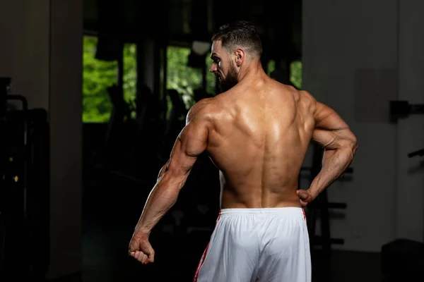 Schöner Junger Mann Der Stark Fitnessstudio Steht Und Die Muskeln — Stockfoto