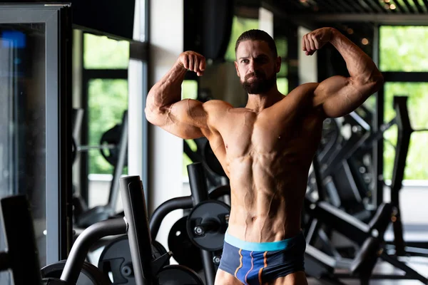 Schöner Junger Mann Der Stark Fitnessstudio Steht Und Die Muskeln — Stockfoto