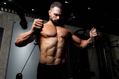 Güzel kaslı vücut geliştirici. Spor salonunda kablolu TV ile Göğüs Üstünde Ağırlık Egzersizi Yapıyor.