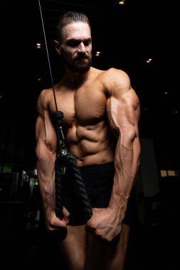 Spor salonunda makinede Triceps için ağır egzersiz yaparak genç kas Fitness vücut geliştirmeci