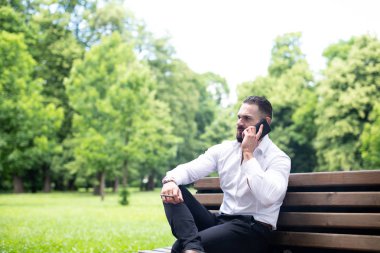 Genç bir portresi, fiziksel olarak işadamı sigara Küba purosu Park ve cep telefonu üzerinde görüşmeler uygun