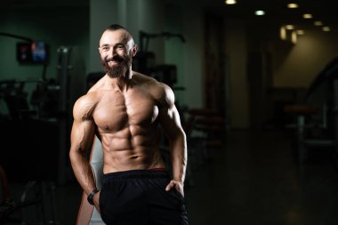 Yakışıklı ve çekici bir genç adam. Vücut kasları spor salonunda dinleniyor.