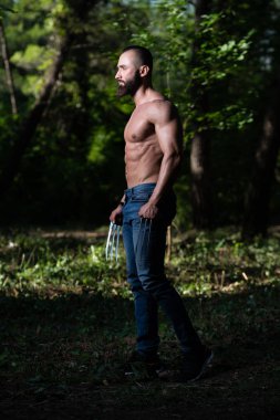 Wolverine güçlü ayakta açık havada ve kasların esneme - pençeleri ile atletik süper kahraman poz