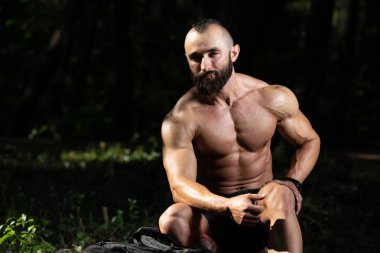 Yakışıklı genç Model güçlü açık havada oturma ve kas - poz kaslı atletik vücut geliştirmeci Man - esneme metniniz için bir yer