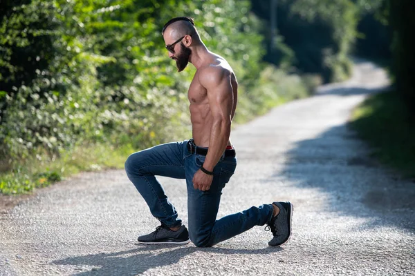 健康的年轻男子跪强弯曲肌肉 肌肉运动健美健身模型摆在户外 — 图库照片